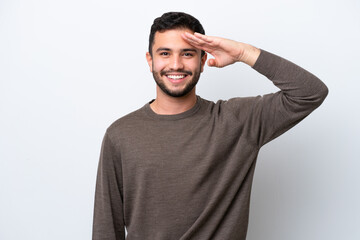 Young Brazilian man isolated on white background saluting with hand with happy expression