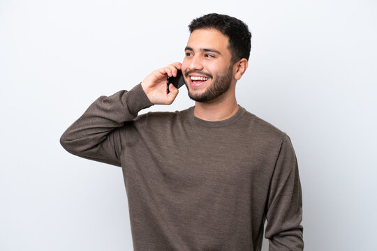 Young Brazilian man isolated on white background keeping a conversation with the mobile phone