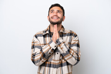 Fototapeta premium Young Brazilian man isolated on white background keeps palm together. Person asks for something