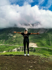 A girl on the background of beautiful green mountains in Dagestan with clouds. Russia.