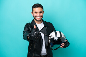 Young Brazilian woman with a motorcycle helmet isolated on blue background with thumbs up because...