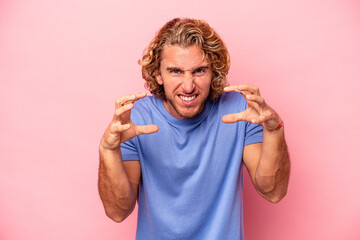 Young caucasian man isolated on pink background upset screaming with tense hands.