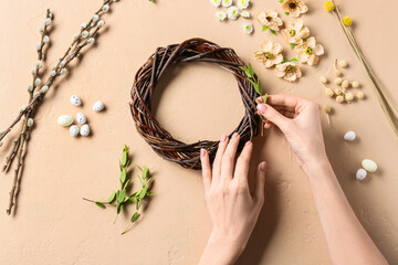 Woman making Easter wreath on beige background