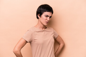 Young caucasian woman isolated on beige background frowning face in displeasure, keeps arms folded.