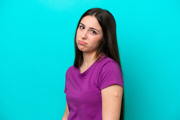 Obraz premium Young girl with band-aids isolated on blue background with sad expression