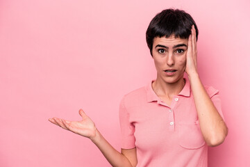 Young caucasian woman isolated on pink background impressed holding copy space on palm.