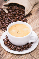 White cup of coffee and roasted fragrant dark coffee grains
