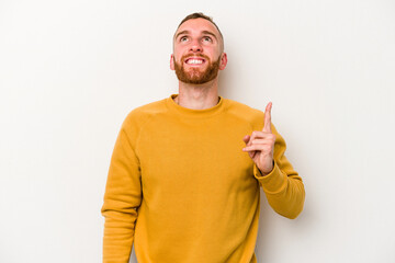 Young caucasian man isolated on white background indicates with both fore fingers up showing a...