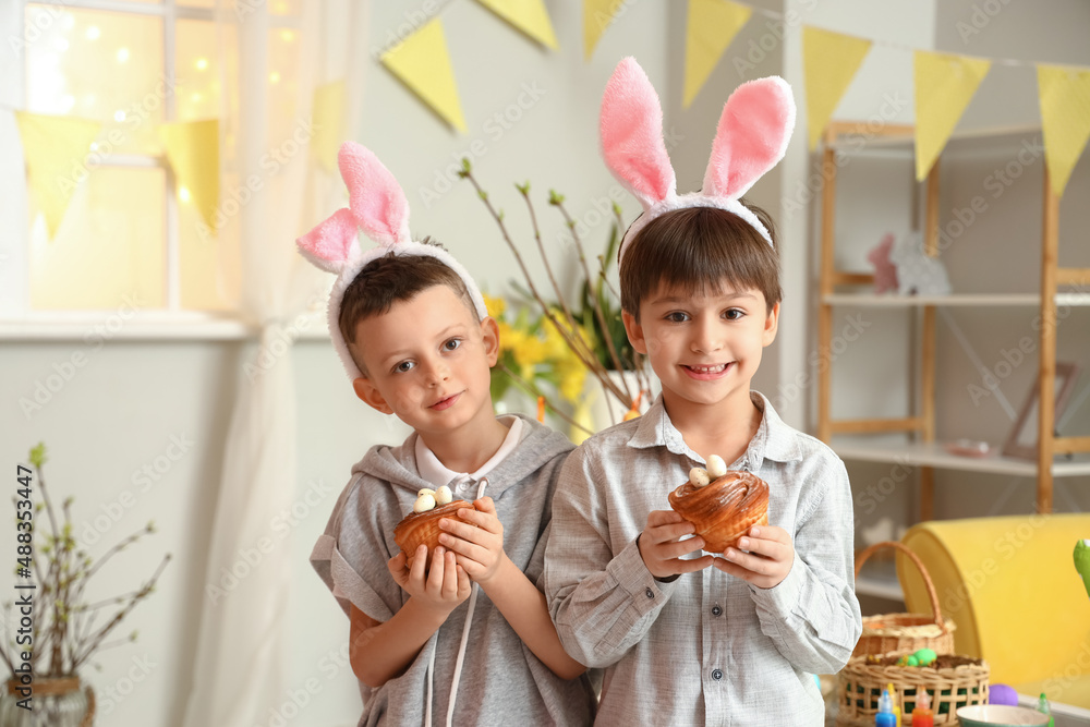 Poster Cute little boys with bunny ears and Easter cakes at home