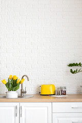 Interior of light kitchen with bouquet of tulips in sink