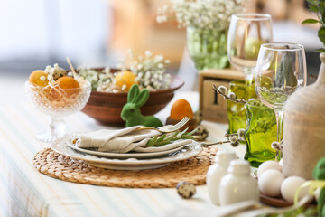 Plates with napkin, cutlery and eucalyptus branch on table served for Easter celebration