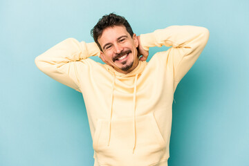 Young caucasian man isolated on blue background stretching arms, relaxed position.