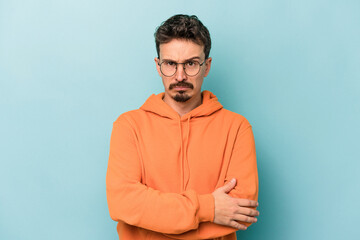 Young caucasian man isolated on blue background unhappy looking in camera with sarcastic expression.