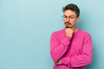 Young caucasian man isolated on blue background looking sideways with doubtful and skeptical expression. - obrazy, fototapety, plakaty