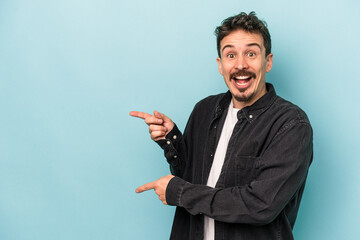 Young caucasian man isolated on blue background excited pointing with forefingers away.
