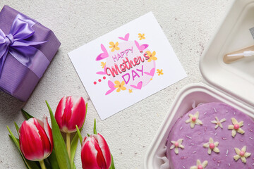 Plastic lunch box with tasty bento cake, greeting card and flowers on light background