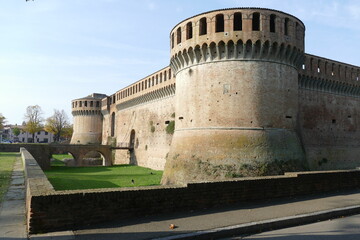 Sforza Castle in Imola, the main building with ravines sorrouded by circular bastions and a moat and a green lawn in front