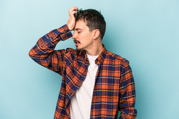 Young caucasian man isolated on blue background forgetting something, slapping forehead with palm...