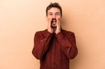 Young caucasian man isolated on beige background saying a gossip, pointing to side reporting something.