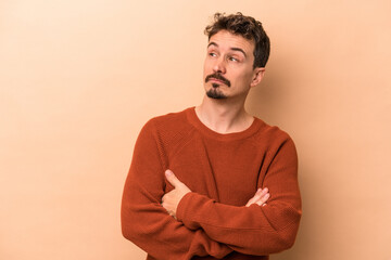 Young caucasian man isolated on beige background dreaming of achieving goals and purposes