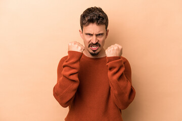 Young caucasian man isolated on beige background upset screaming with tense hands.
