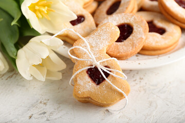 Delicious Easter cookies and tulip flowers on light background, closeup