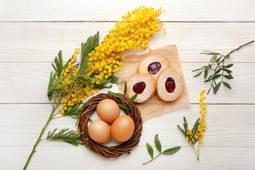 Beautiful Easter composition with tasty cookies, eggs and mimosa branch on light wooden background