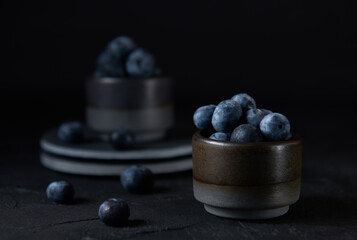 Fresh organic blueberries in a bowl on black background