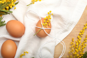 Composition with Easter eggs and beautiful mimosa branches on wooden background