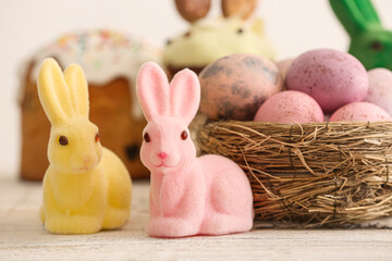 Cute Easter bunnies and nest with eggs on table, closeup