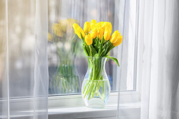 Vase with beautiful yellow tulip flowers on windowsill