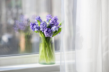 Vase with beautiful hyacinth flowers on windowsill