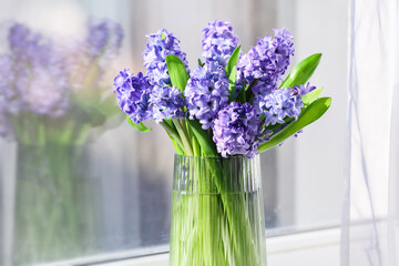 Vase with beautiful hyacinth flowers on windowsill, closeup