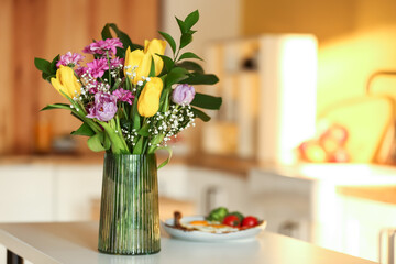 Vase with beautiful flowers on dining table in kitchen