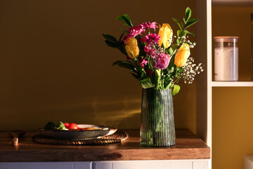 Vase with bouquet of beautiful flowers and breakfast on kitchen counter