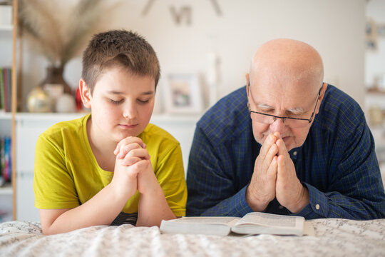 Grandfather praying at the edge of the bed with his nephew