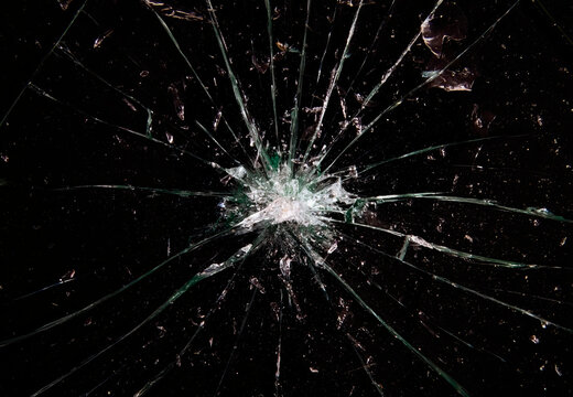 A broken glass on a black background, a big hole at the center and many shattered pieces around it. A useful texture, overlay or background.
