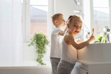 Children brother and sister wash and brush their teeth in the bathroom