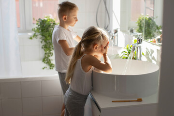 Children brother and sister wash and brush their teeth in the bathroom