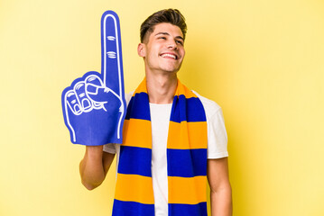 Young sports fan man isolated on yellow background dreaming of achieving goals and purposes © Asier