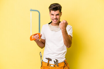 Young electrician caucasian man isolated on yellow background.showing fist to camera, aggressive...