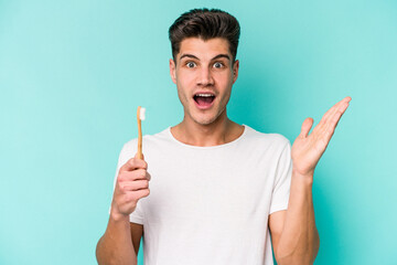 Young caucasian man brushing teeth isolated on white background surprised and shocked.