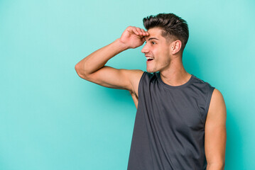 Young caucasian man isolated on blue background looking far away keeping hand on forehead.