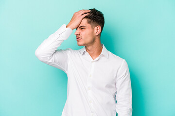 Young caucasian man isolated on blue background forgetting something, slapping forehead with palm...