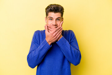 Obraz premium Young caucasian man isolated on yellow background shocked covering mouth with hands.