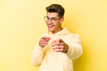 Young caucasian man isolated on yellow background pointing to front with fingers.