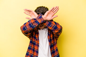 Young caucasian man isolated on yellow background keeping two arms crossed, denial concept.