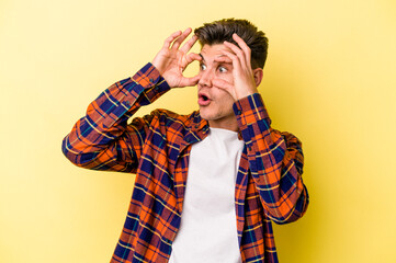 Young caucasian man isolated on yellow background keeping eyes opened to find a success opportunity.