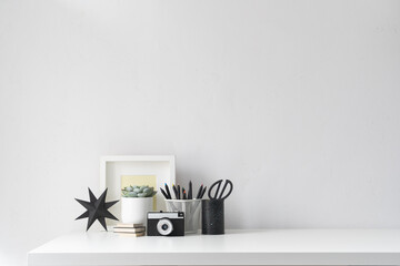 Home office desk with office supplies and neutral white wall.	