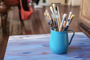 Various professional paint brushes in the blue metal jar, selective focus